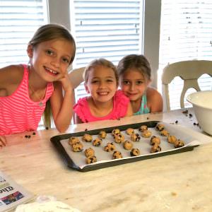 three young girls baking cookies